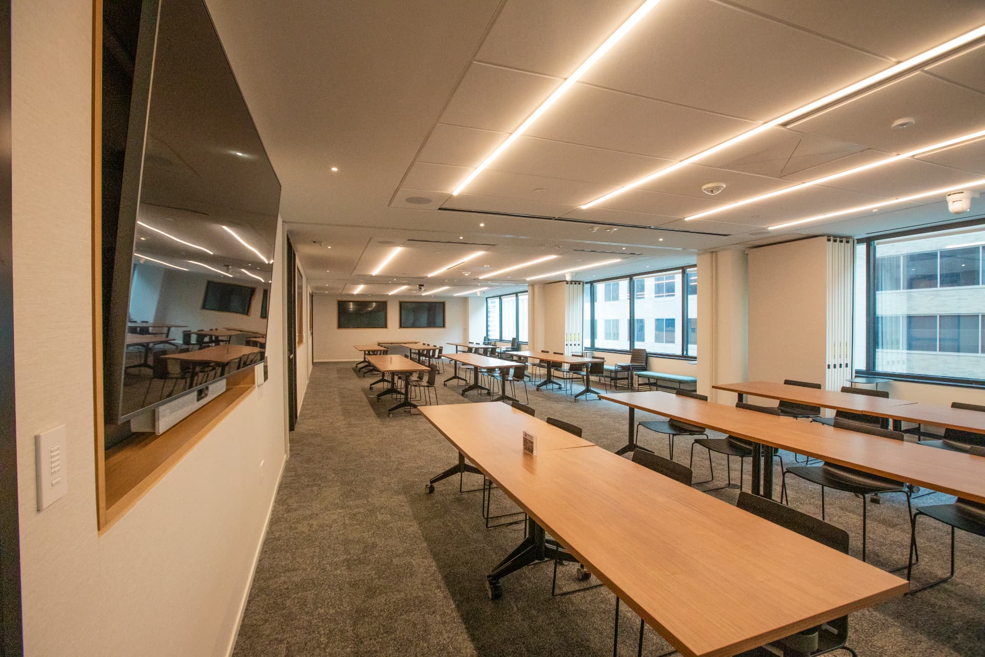 Conference room at 1400 K Street set classroom-style with wood tables and wall-mounted screens