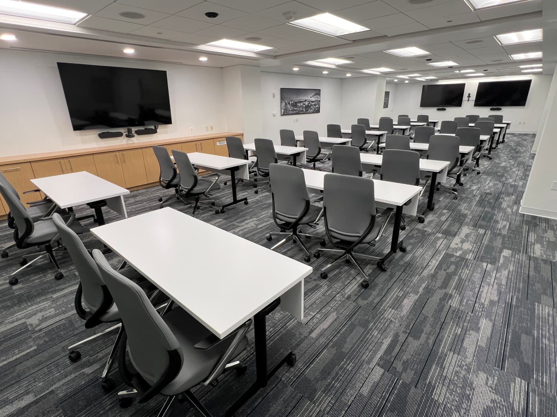 Fourth floor conference room set classroom style with tables, ergonomic chairs, and wall-mounted screens
