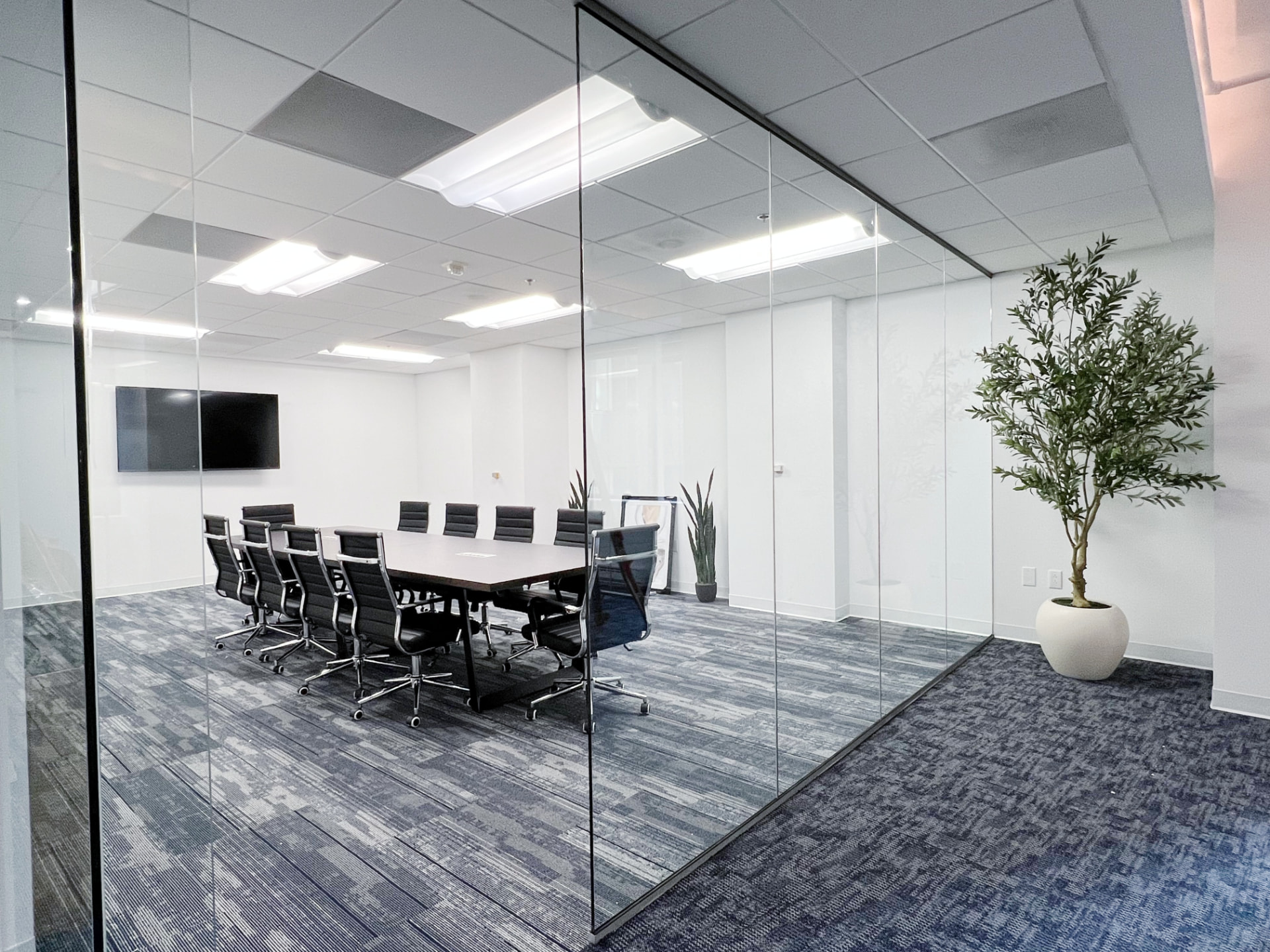 Modern glass-walled conference room with executive seating and a large table
