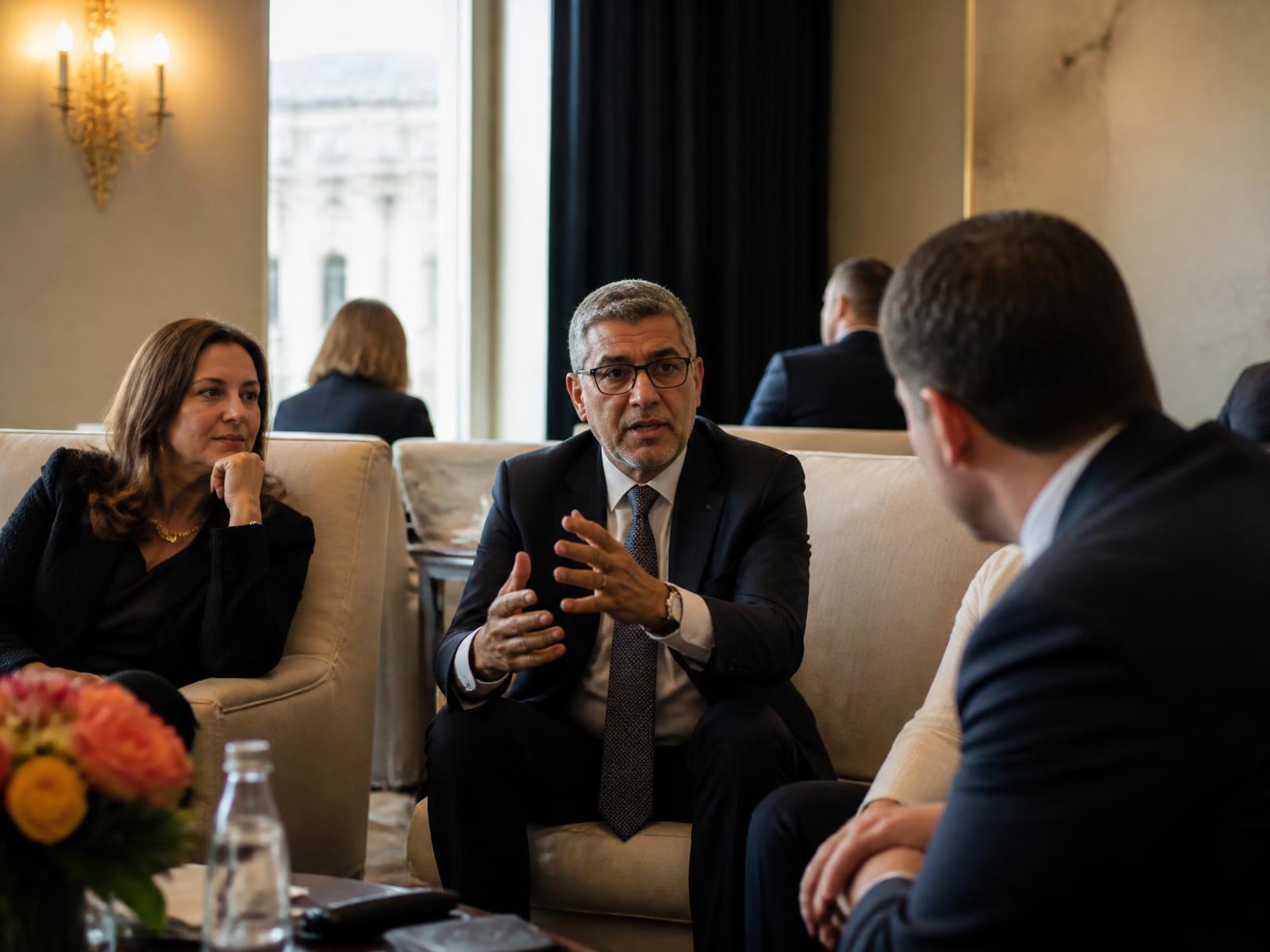 Three professionals in candid conversation in a warmly lit Washington, D.C. meeting lounge